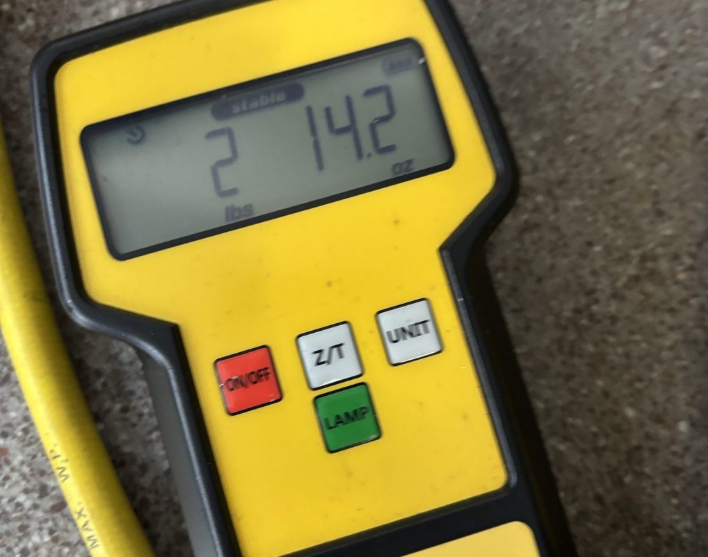 Digital refrigerant scale with a charging hose, used to weigh refrigerant during AC service