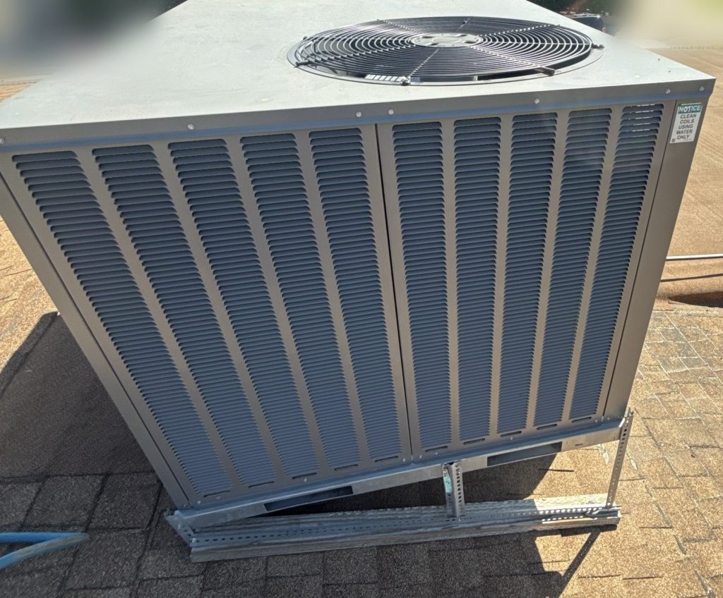 Rooftop package AC unit on a shingle roof, mounted on a metal stand