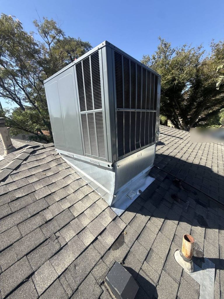 Rooftop package unit on a shingle roof, mounted on a sheet-metal curb